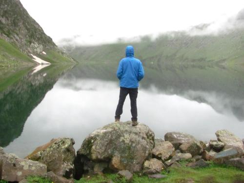 a man standing on a rock in front of a lake at Kashmir Outlook Adventures in Pahalgām