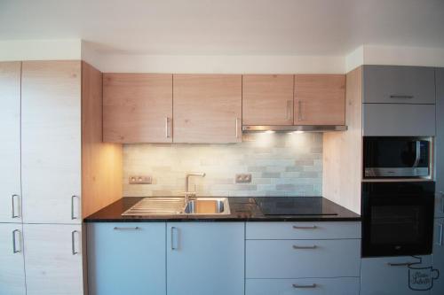 a kitchen with white cabinets and a sink and a microwave at Studio Juliette in Stavelot