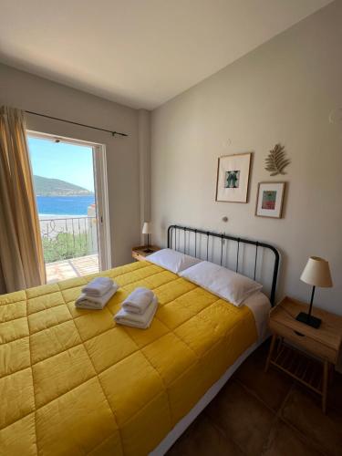 a bedroom with a large yellow bed with a window at Atalanti Apartments in Kyparíssion