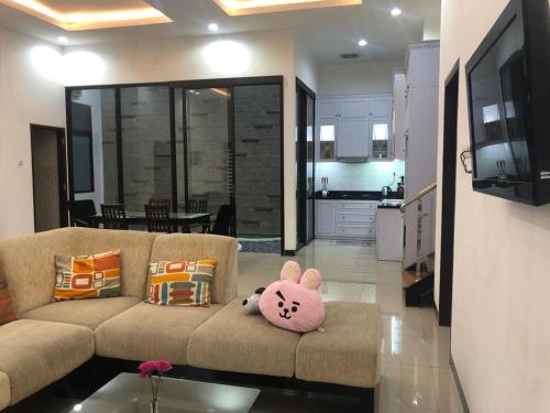 New 3br The Green Home في Kepiting-kidul: غرفة معيشة مع أريكة مع وسادة قطة ترحيبية