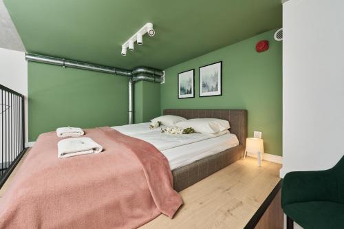 a bedroom with green walls and a bed with a pink blanket at Airport Apartments Zarembowicza by Renters in Wrocław