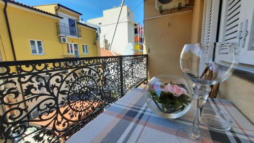 Ein Tisch mit zwei Weingläsern und Blumen auf einem Balkon in der Unterkunft APP BENI in Crikvenica