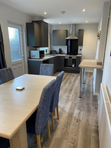 uma cozinha com uma grande mesa de madeira e cadeiras em Spacious & modern 3 bed house em Stafford