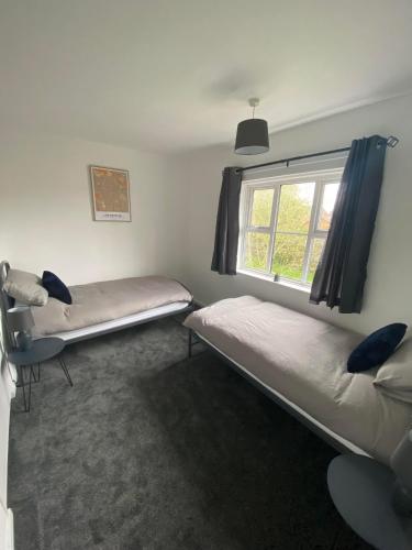 a room with two beds and a window at Spacious & modern 3 bed house in Stafford