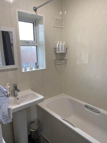 a white bathroom with a tub and a sink at Spacious & modern 3 bed house in Stafford