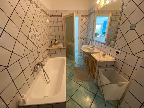 a bathroom with a tub and a sink and a mirror at Le Dimore di Zaro - Green Paradise in Forio d'Ischia