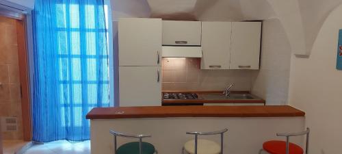 a kitchen with white cabinets and a counter with bar stools at In Vacanza a Gaeta - Libera Stella in Gaeta