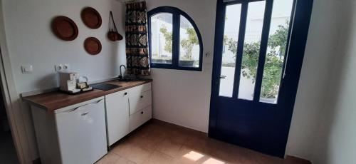 cocina con puerta azul y armarios blancos en Agia Roumeli APARTMENT, en Agia Roumeli