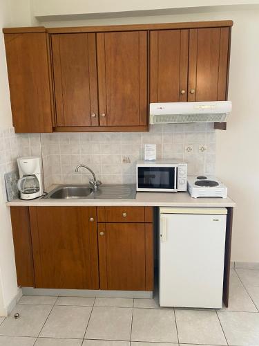 a kitchen with a sink and a microwave at Poseidon Studios & Apartments in Palaiochóra