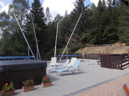 a patio with two white chairs and a boat at Pension U Jelinka in Nové Hamry