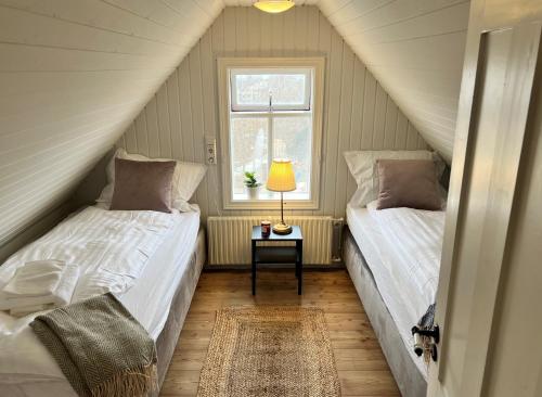 a attic bedroom with two beds and a window at Day Dream Central Akureyri Three Bedroom Apt in Akureyri