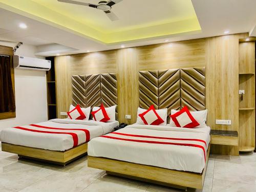 two beds in a hotel room with red pillows at The Eleganza in Jhājra
