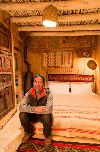 a man sitting on the edge of a bed at Dar KamalChaoui in Bhalil