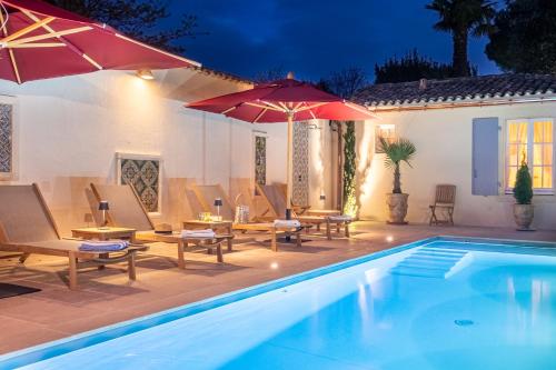 a pool with chairs and umbrellas next to a house at La Baronnie Hôtel & Spa - Teritoria in Saint-Martin-de-Ré