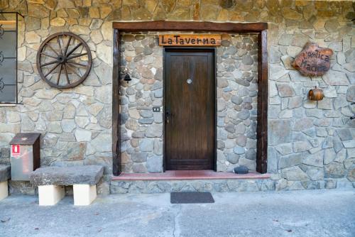 kamienny budynek z drewnianymi drzwiami z napisem w obiekcie Antica Macina - “La Taverna” w mieście Rocchetta Nervina