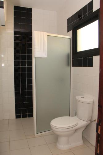 a bathroom with a toilet and a glass shower door at Résidence Hôtelière Lauria in Lomé