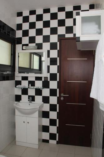 a bathroom with a sink and a checkered wall at Résidence Hôtelière Lauria in Lomé