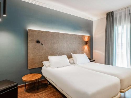 una habitación de hotel con una gran cama blanca y una mesa en Ibis Styles Figueres Ronda, en Figueres