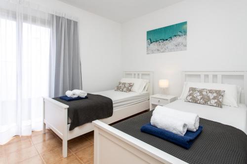 a white bedroom with two beds and a window at Luxury Villa Perla in Caleta De Fuste