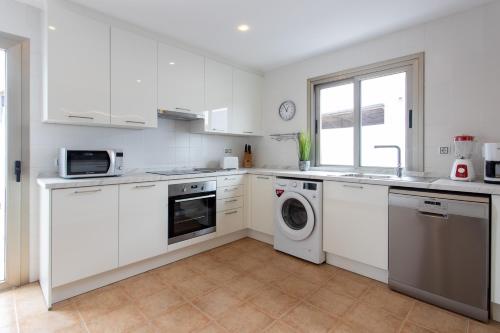 a kitchen with white cabinets and a washer and dryer at Luxury Villa Perla in Caleta De Fuste