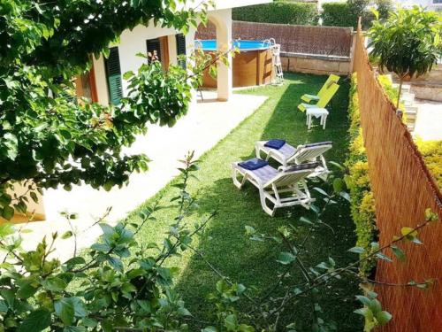 einen Garten mit Gartenstühlen und einem Zaun in der Unterkunft *****Villa de Món max. 8 Personen, Meerblick + Pool in Cala Anguila