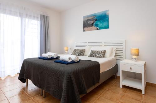 a white bedroom with a bed with towels on it at Luxury Villa Perla in Caleta De Fuste