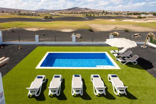 a pool with chaise lounge chairs and an umbrella at Luxury Villa Perla in Caleta De Fuste
