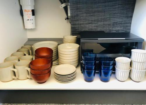 a shelf filled with cups and plates and blue glasses at Corner6 in Kyoto
