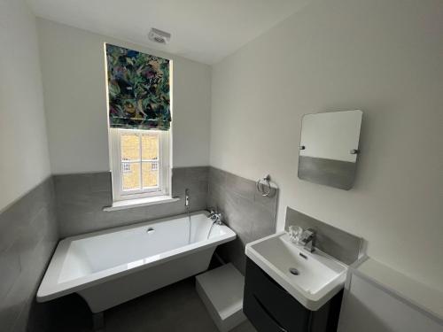 a bathroom with a tub and a sink and a window at Dockers Inn in London