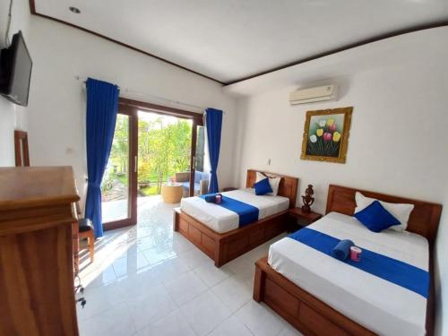 a bedroom with two beds and a tv and a window at Bobo Bungalow in Nusa Lembongan