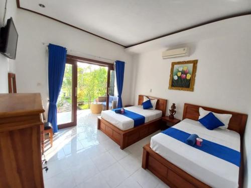 Un dormitorio con dos camas y un televisor y una ventana. en Bobo Bungalow, en Nusa Lembongan
