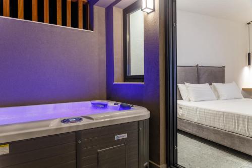 a purple bathroom with a tub next to a bed at Utopia Luxury Suites in Platanes