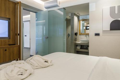 a bedroom with a white bed and a bathroom at Utopia Luxury Suites in Platanes