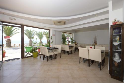 a dining room with a table and chairs and the ocean at Hotel Akrogiali in Ouranoupoli