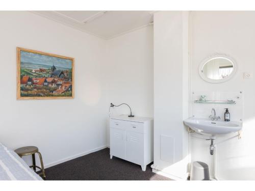 ein weißes Badezimmer mit einem Waschbecken und einem Spiegel in der Unterkunft Spacious holiday home with sunny garden 150 meters from the beach and shops in Zoutelande