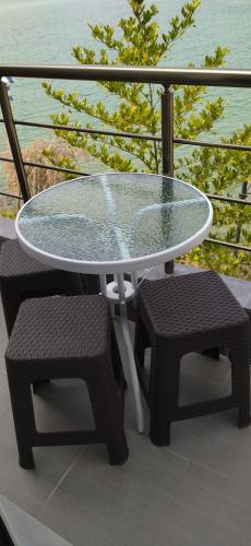 a glass table and two chairs on a balcony at Ilio Socrates in Skala Marion