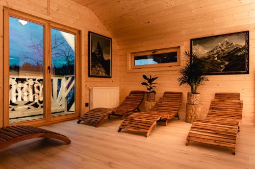 a room with wooden chairs and a balcony at Osada Chłabówka Zakopane & SPA in Zakopane