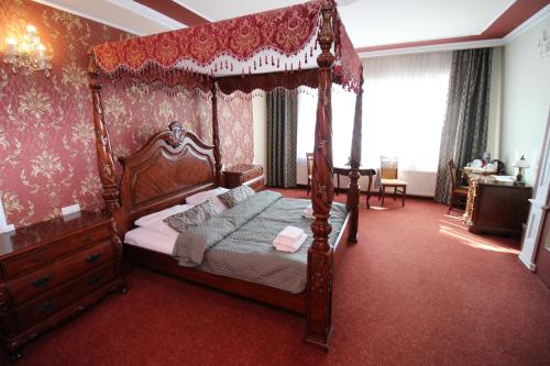 a bedroom with a canopy bed and red carpet at Złote Arkady in Częstochowa