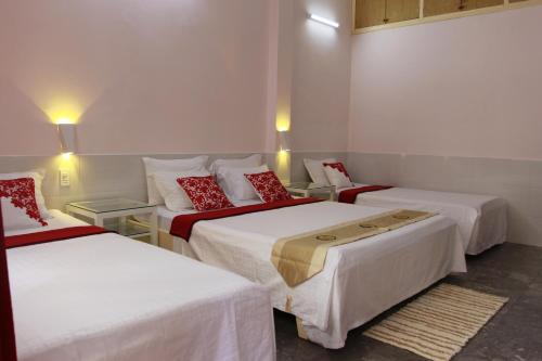 a room with three beds with white sheets and red pillows at QUANG SAIGON Hotel- 40-7 Bùi Viện-Walking street in Ho Chi Minh City