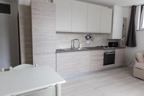 una cocina con armarios blancos y fregadero en Appartamento Speranza, en Molina di Ledro