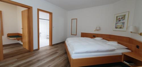 a bedroom with a white bed and a bathroom at Hotel Schön in Aßmannshausen