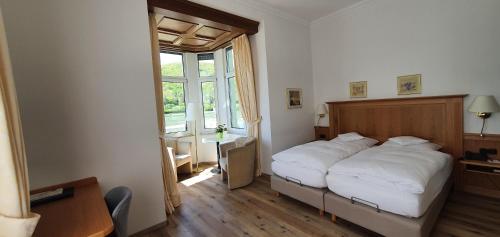 a bedroom with a white bed and a window at Hotel Schön in Aßmannshausen