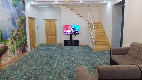 a living room with a television and a staircase at Tomaris in Nukus