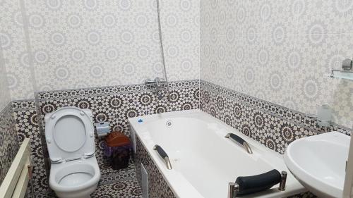 y baño con bañera, aseo y lavamanos. en Tomaris, en Nukus