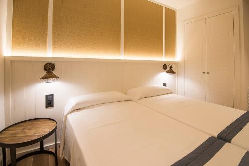 a bedroom with a white bed and a wooden table at Hotel Els Pins in Platja  d'Aro