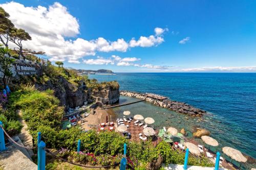 a beach with a bunch of umbrellas and the ocean at Hotel La Madonnina in Ischia