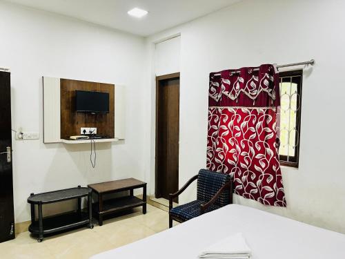 Habitación con cama, silla y TV. en Hotel Airlines, en Calcuta