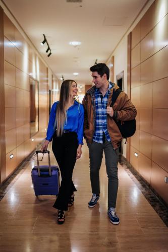 a man and a woman walking down a hallway with a suitcase at Gran Hotel Don Manuel in Cáceres
