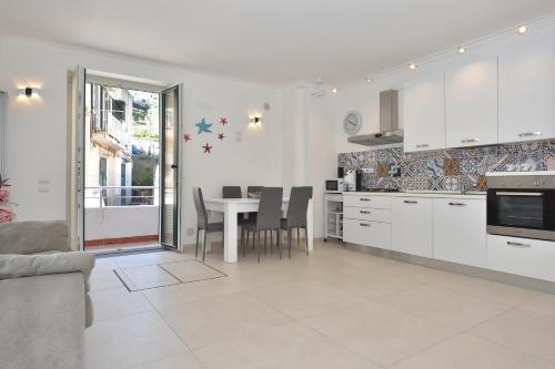 a kitchen with white cabinets and a table with chairs at Sirena Apartment in Minori