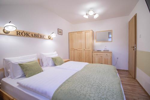 a bedroom with a large bed and a wooden cabinet at Rókabérc Vadászház Hotel in Erdőbénye